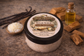 Busy Meadows Vanilla Sandalwood sugar scrub with ingredients on a stone surface