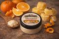 Balm jar with tallow and beeswax on a rustic surface with oranges and beeswax gummies.
