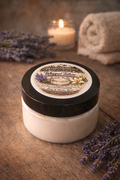 Jar of Busy Meadows Whipped Tallow Balm on a wooden surface with lavender and a candle in the background.