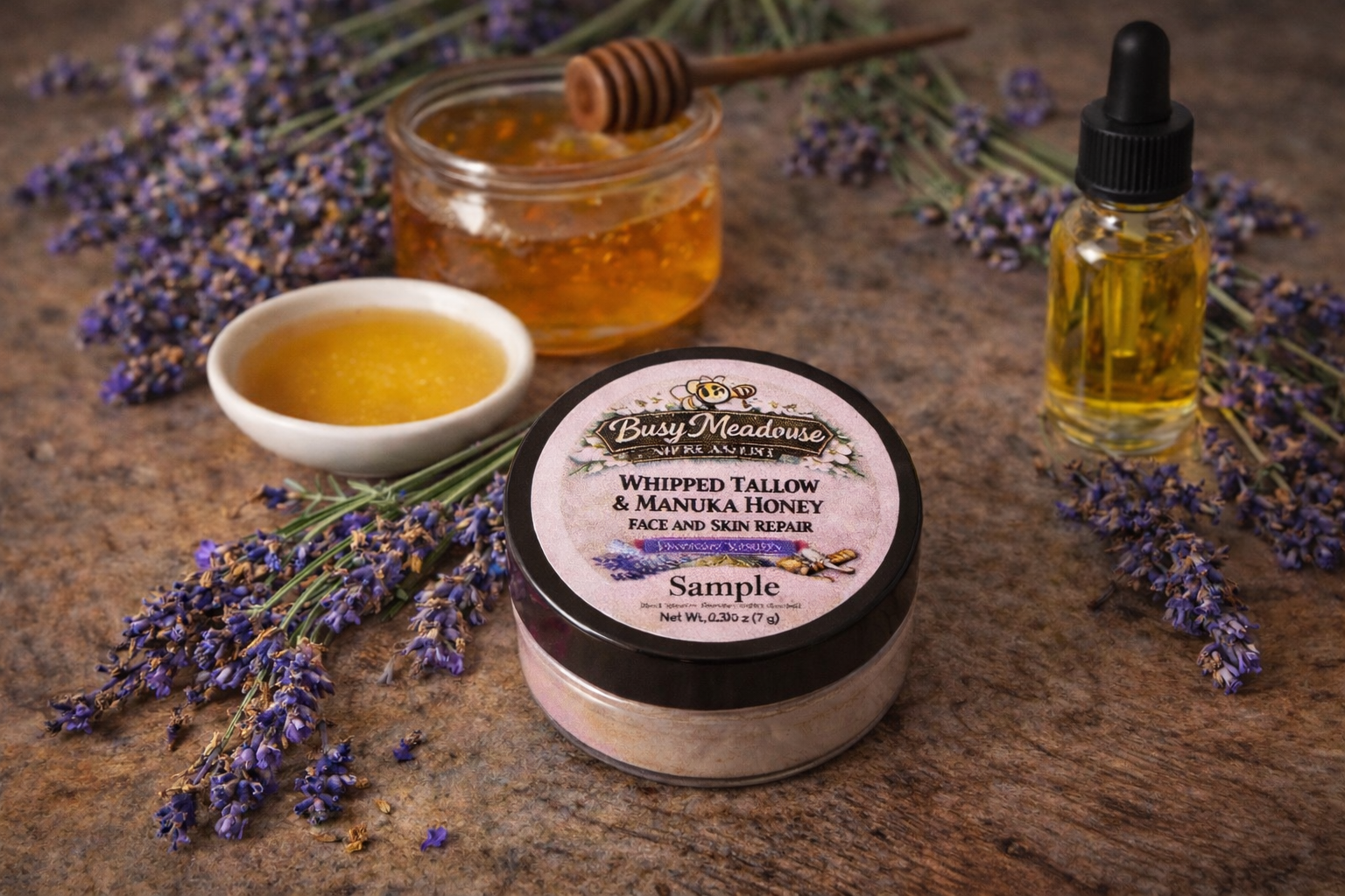 Bath and body products including a jar of whipped tallow and manuka honey, a jar of honey, a bottle of oil, and lavender flowers on a wooden surface.